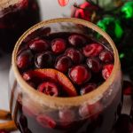 cranberry and orange winter sangria sitting in a glass with a cinnamon sugared rim