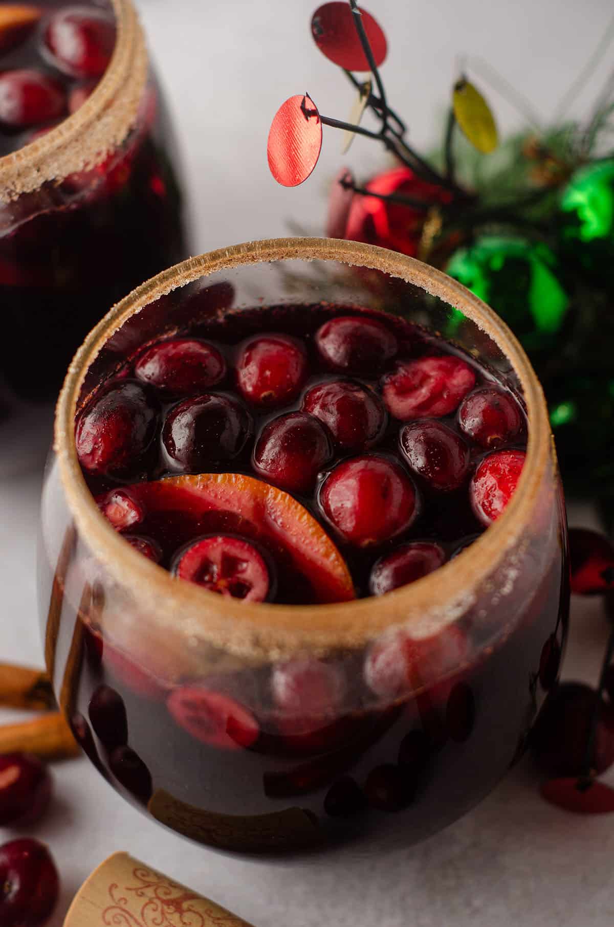 cranberry and orange winter sangria sitting in a glass with a cinnamon sugared rim