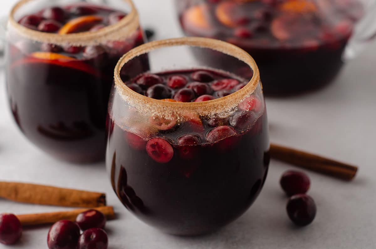 cranberry and orange winter sangria sitting in a glass with a cinnamon sugared rim