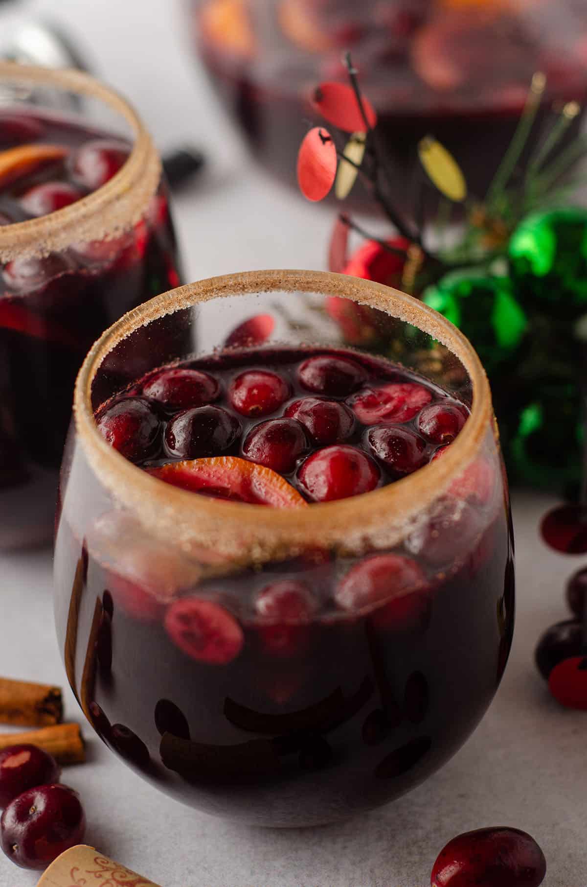 cranberry and orange winter sangria sitting in a glass with a cinnamon sugared rim