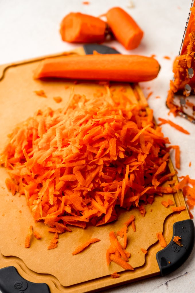 A cutting board with shredded carrots on it.