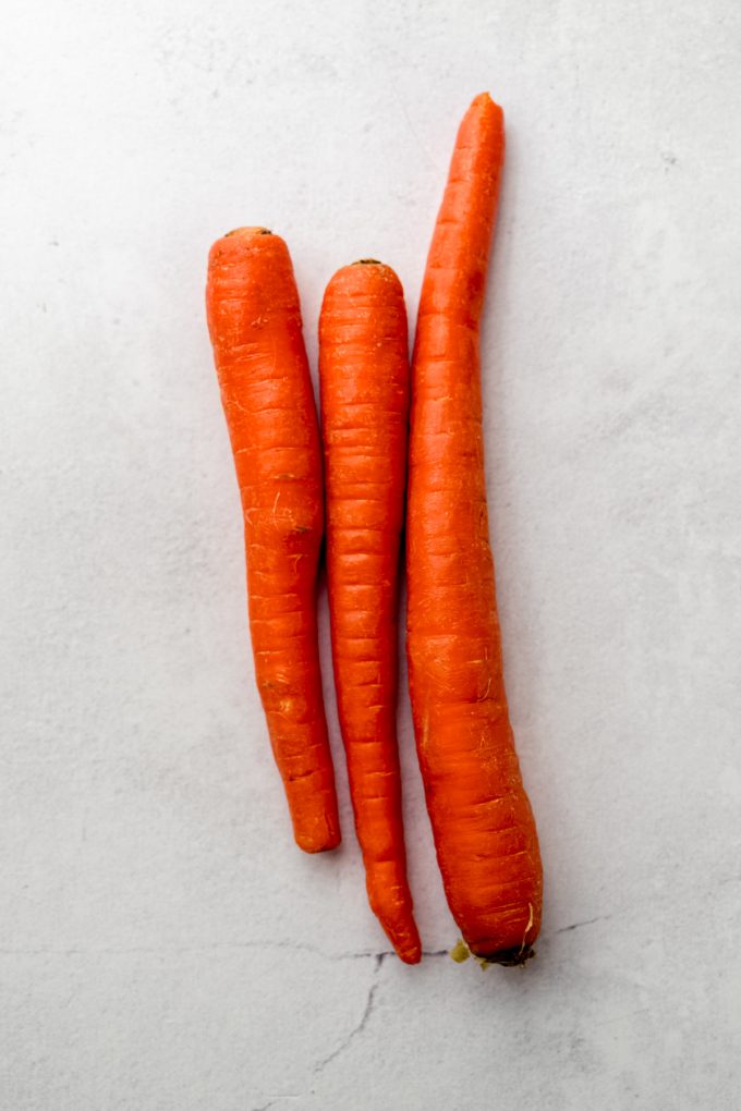 Aerial photo of three large carrots on a surface.