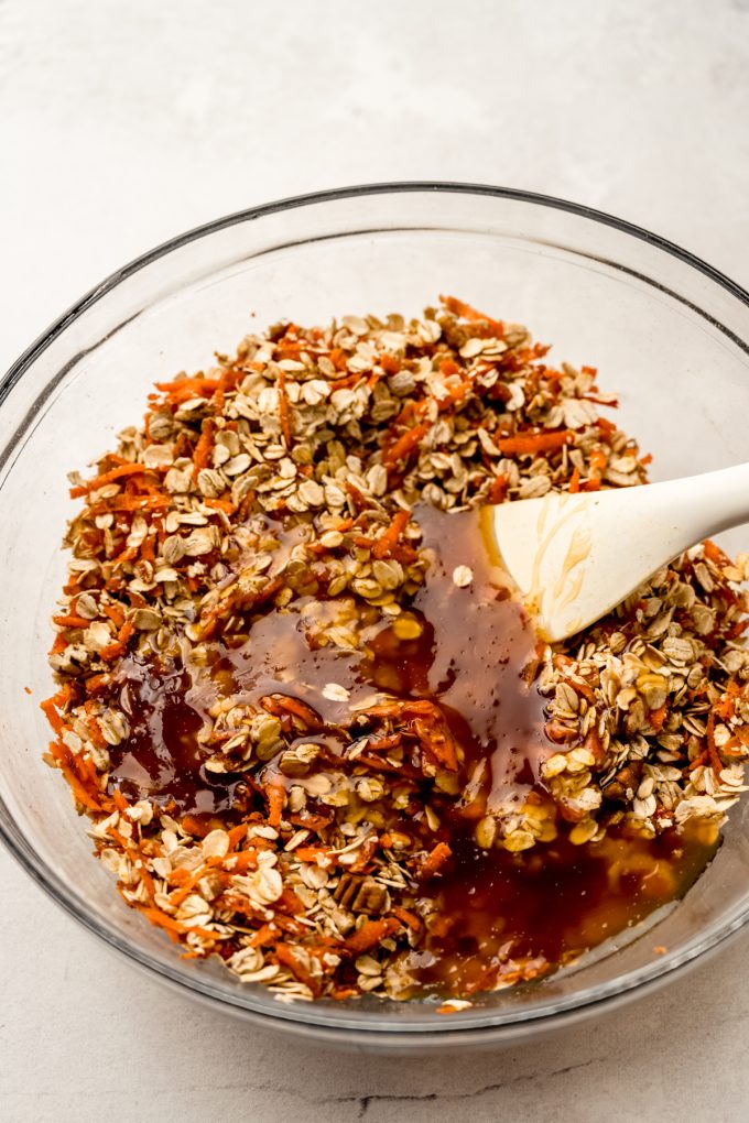 A bowl of carrot cake granola getting stirred together with a spatula.