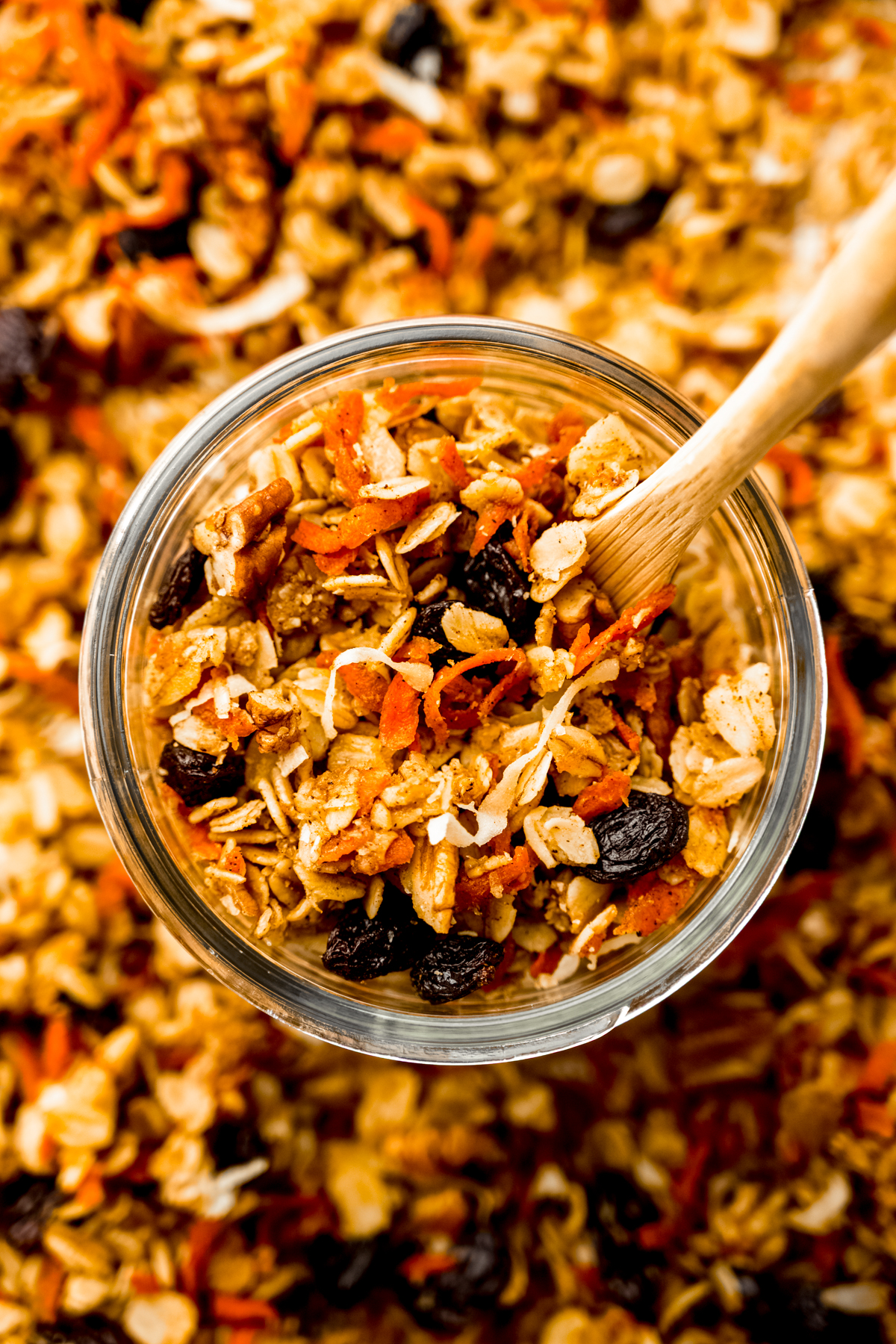 Aerial photo of a jar of carrot cake granola with a wooden spoon in it.