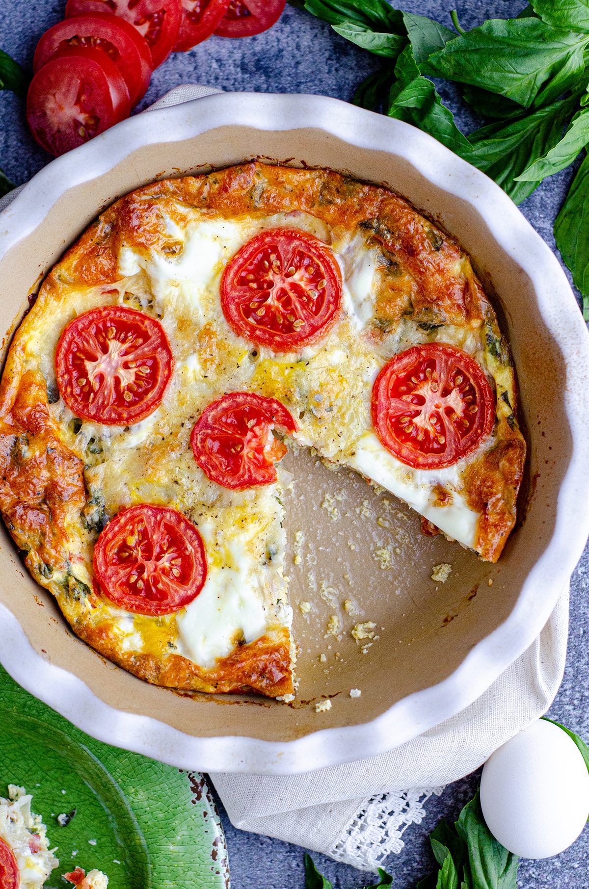 aerial photo of crustless caprese quiche in a pie plate with a slice taken out of it