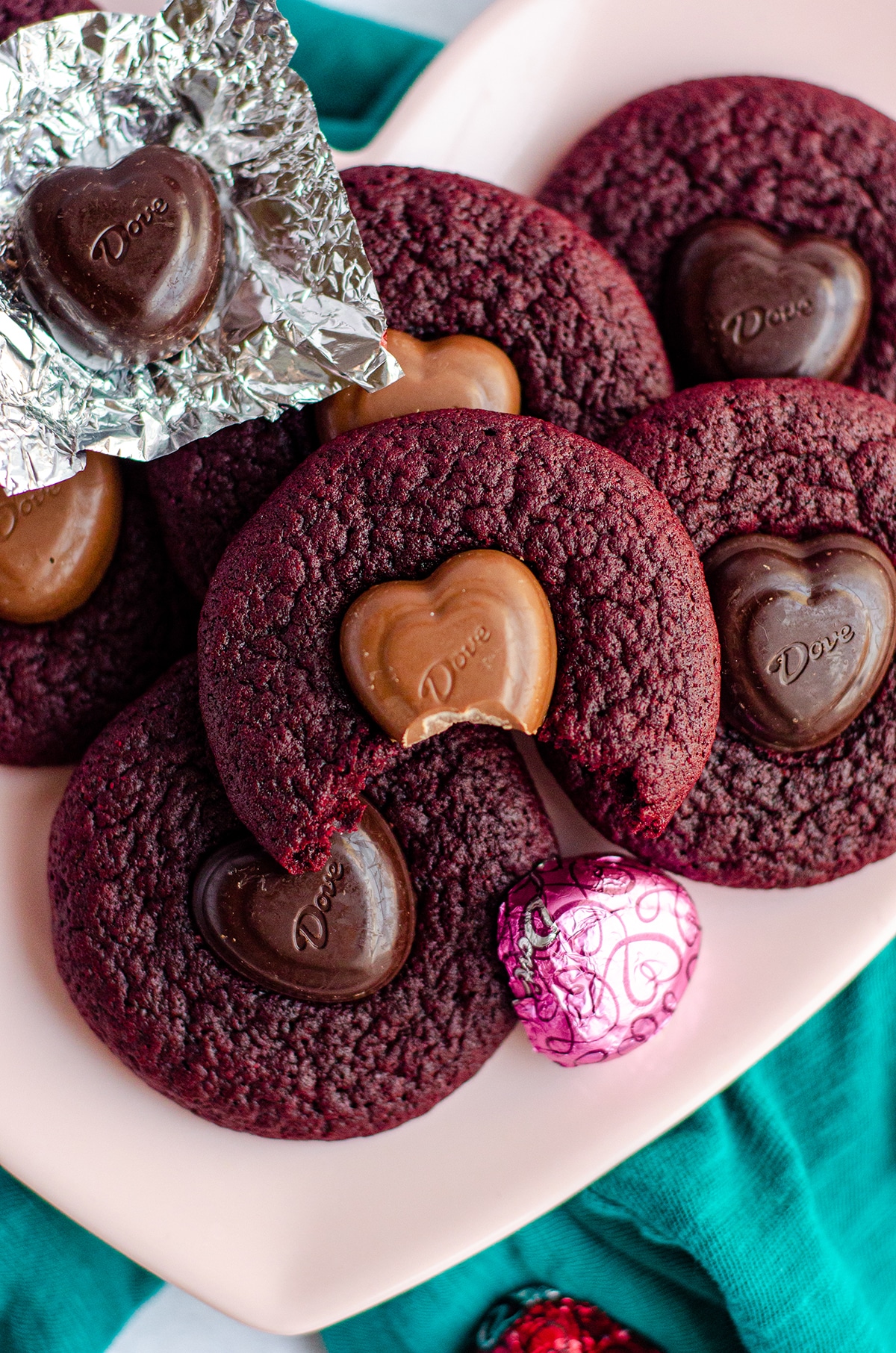 red velvet blossom cookies on a pink plate with a bite taken out of one