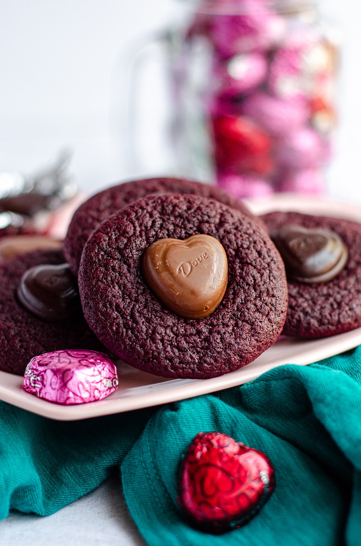 red velvet blossom cookies on a pink plate with wrapped chocolate candies around it