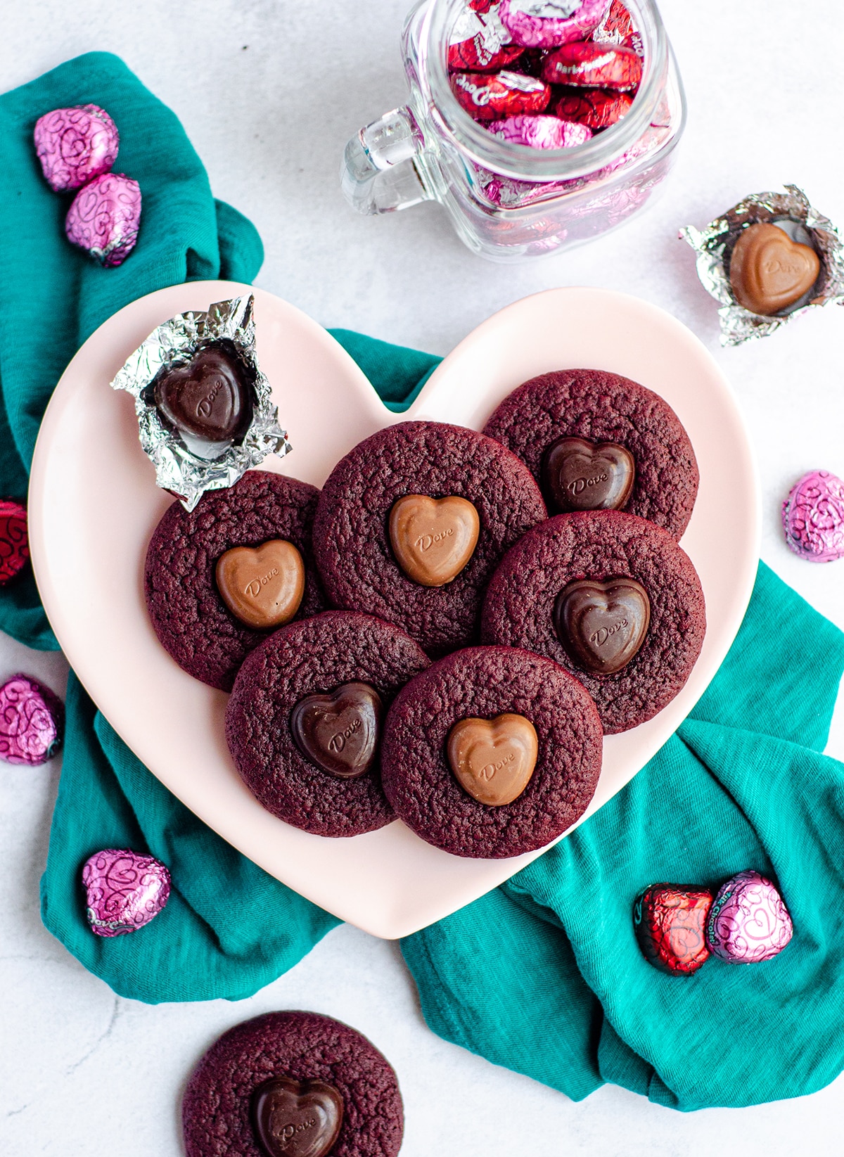 red velvet blossom cookies on a pink heart shaped plate and a teal kitchen towel 