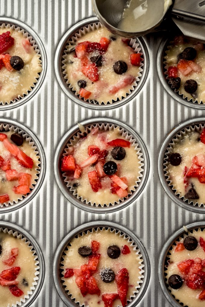 Aerial photo of strawberry chocolate chip muffin batter in the wells of a muffin tin.