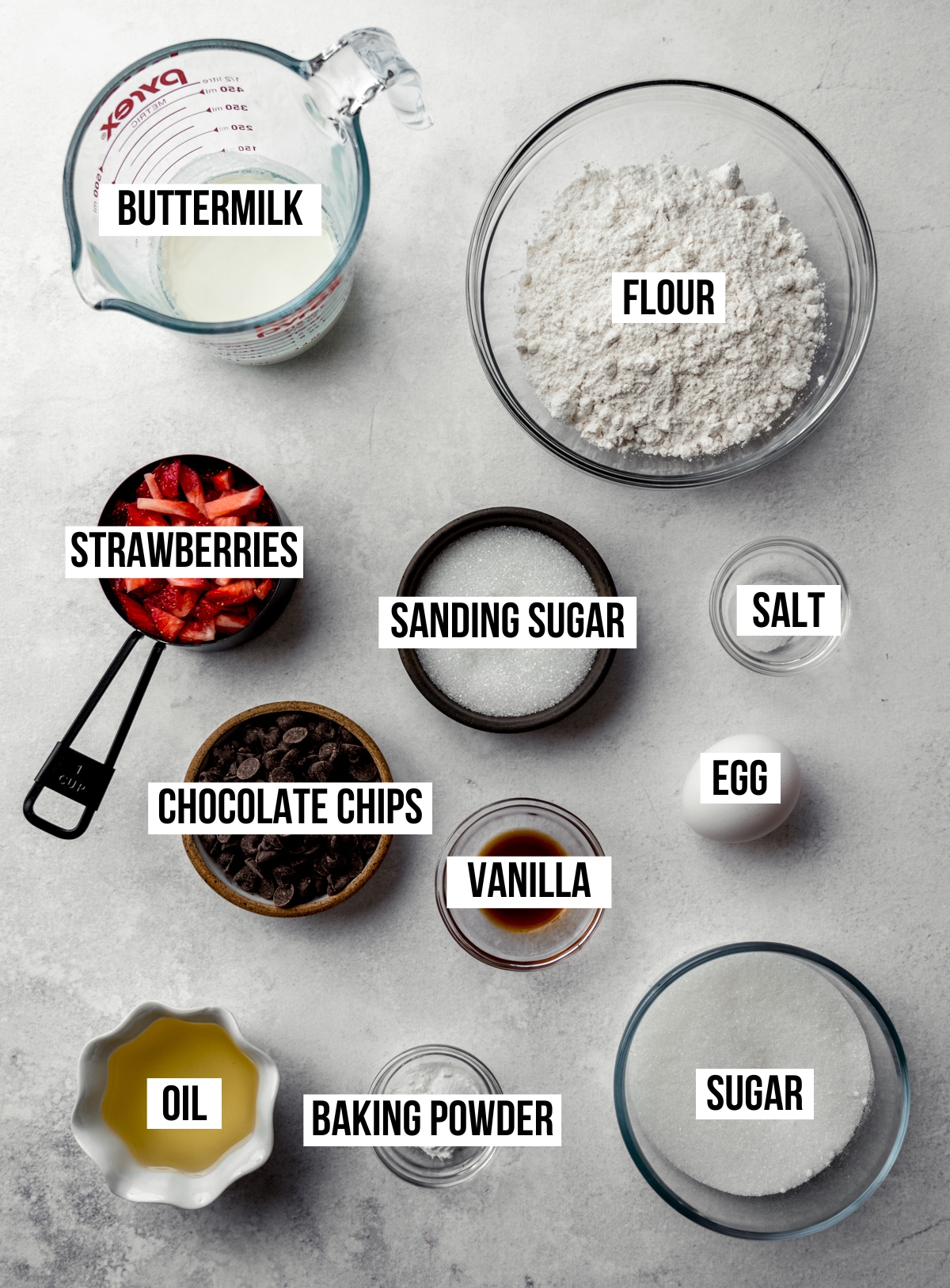 Aerial photo of ingredients to make strawberry chocolate chip muffins with text overlay labeling each ingredient.