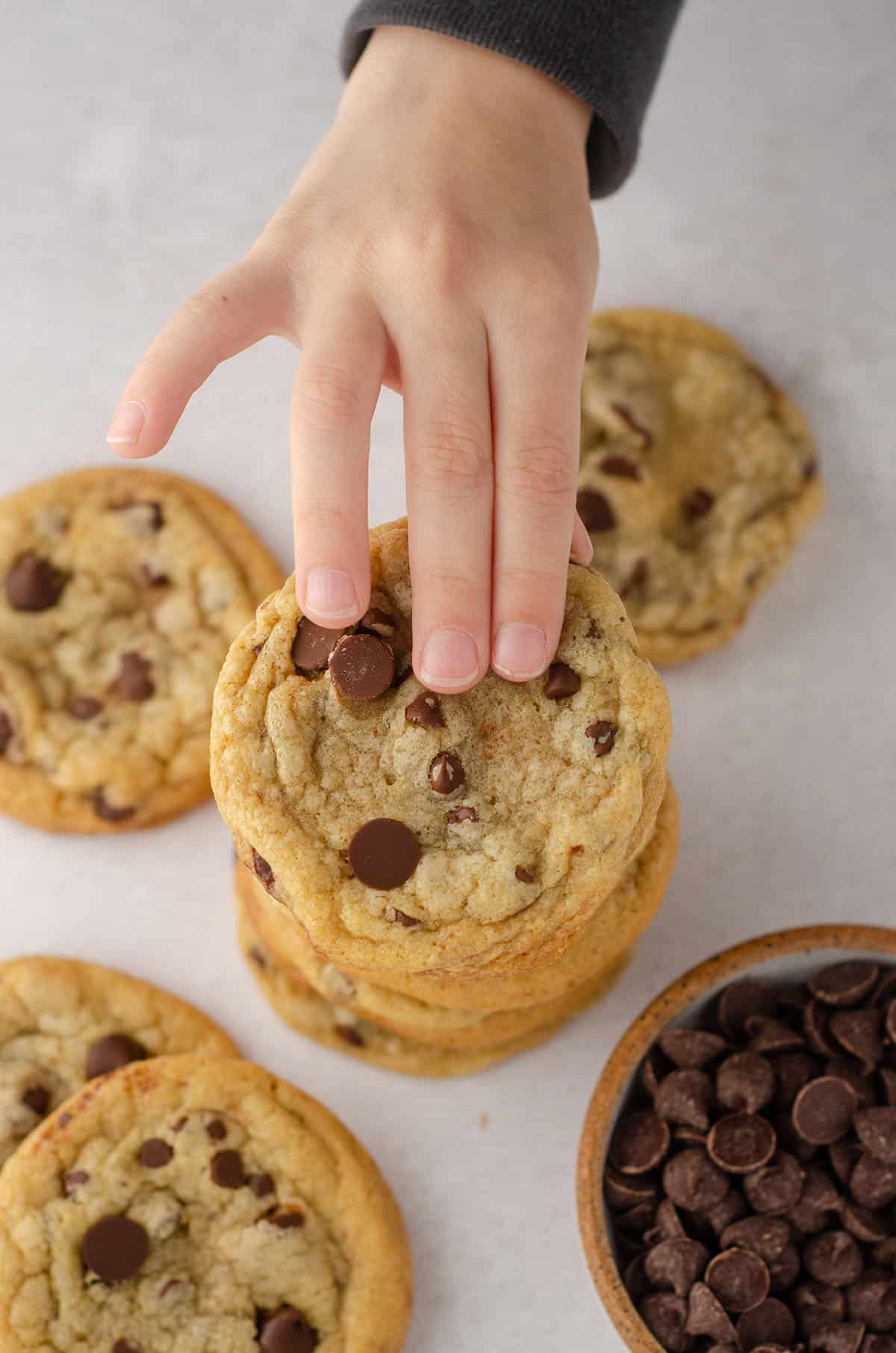 aerial photo of toddler hand reaching to grab a chocolate chip cookies