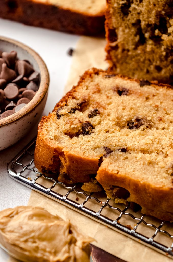 A slice of chocolate chip peanut butter bread on a wire cooling rack.