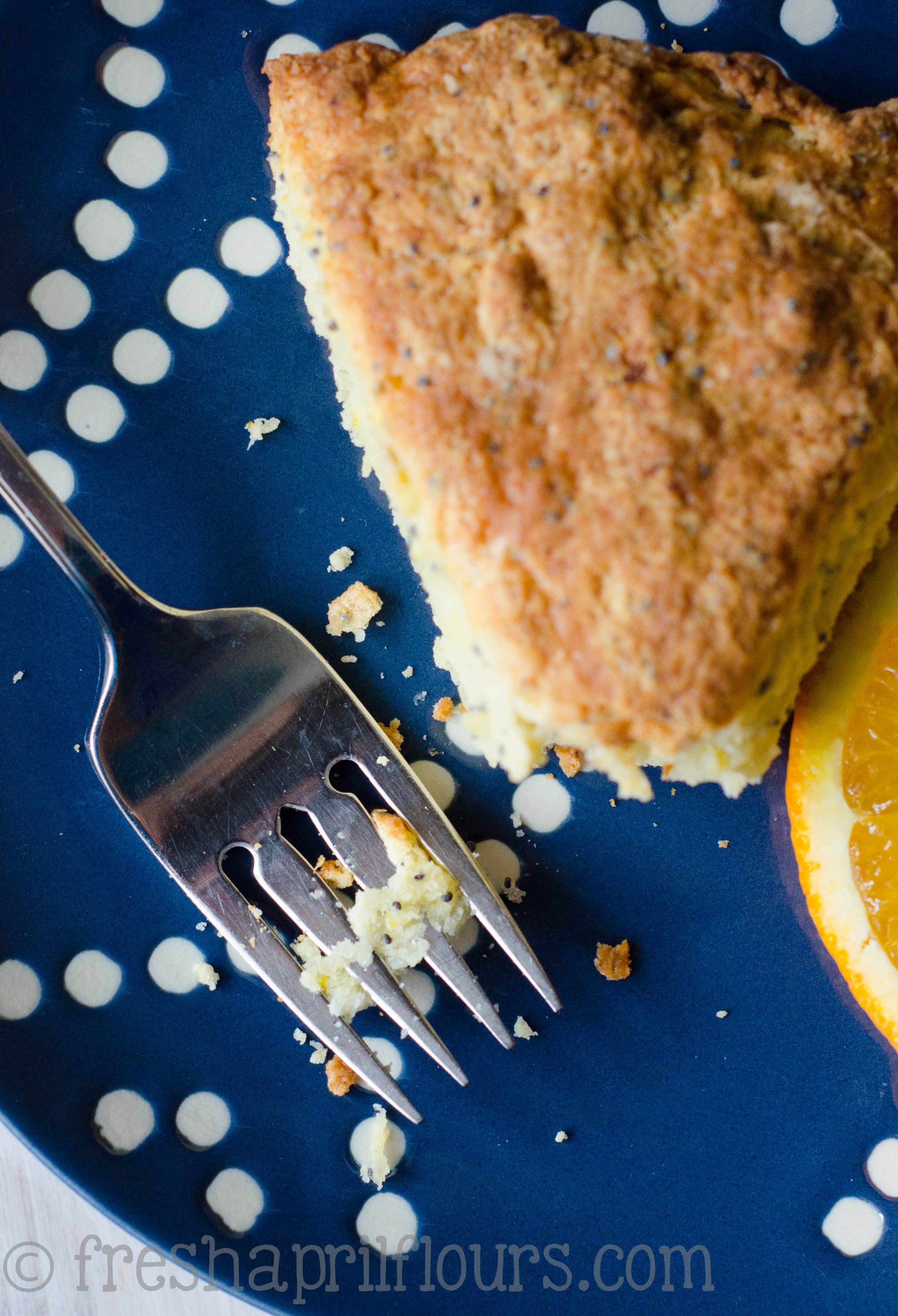 Orange poppy seed scone on a plate with a fork.