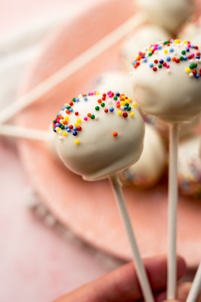 Someone's hand holding a few cake pops.