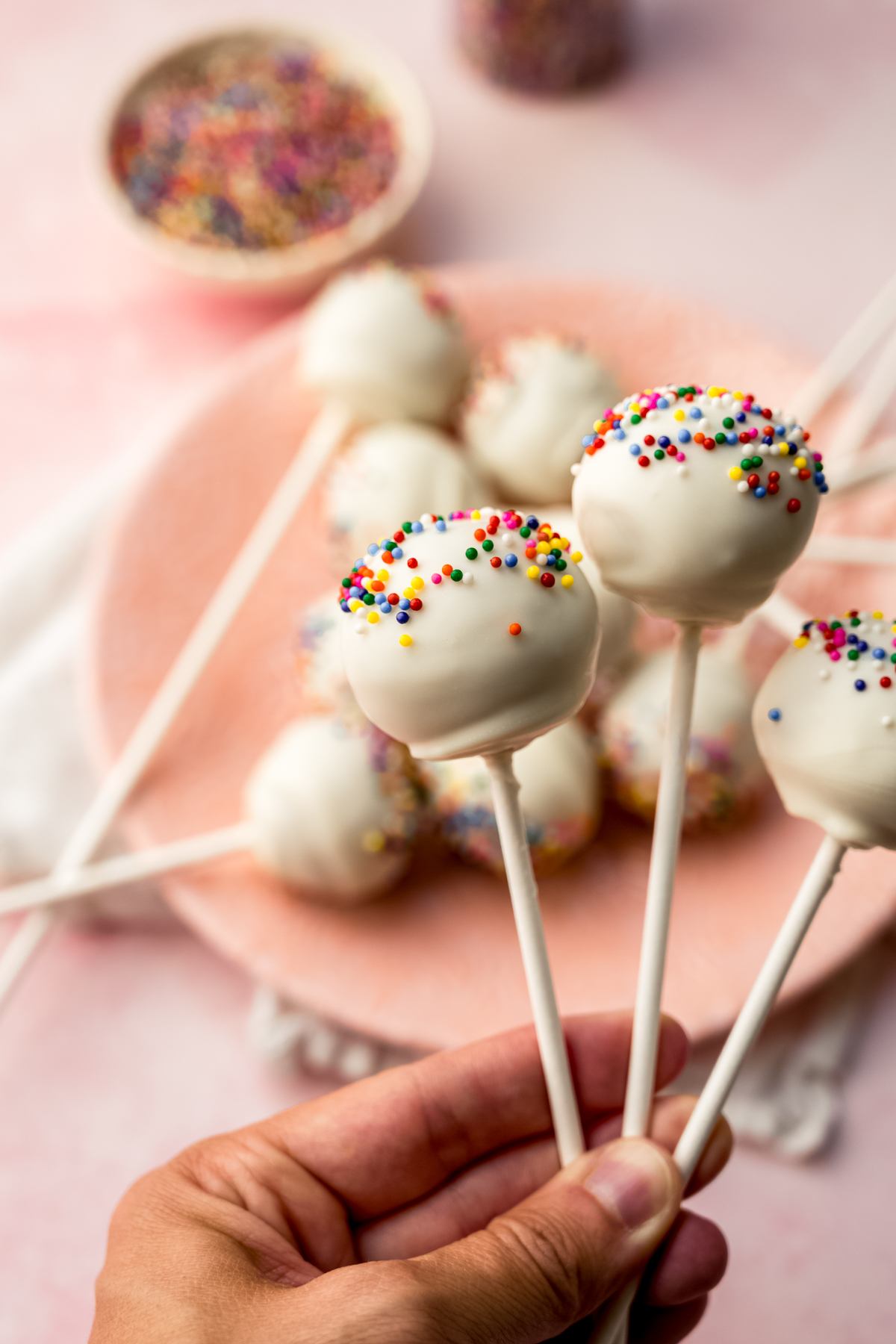 Someone's hand holding a few cake pops.