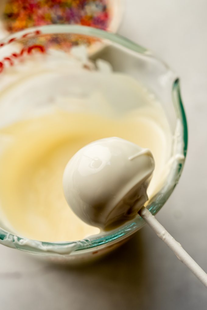 A cake pop getting dipped into coating.