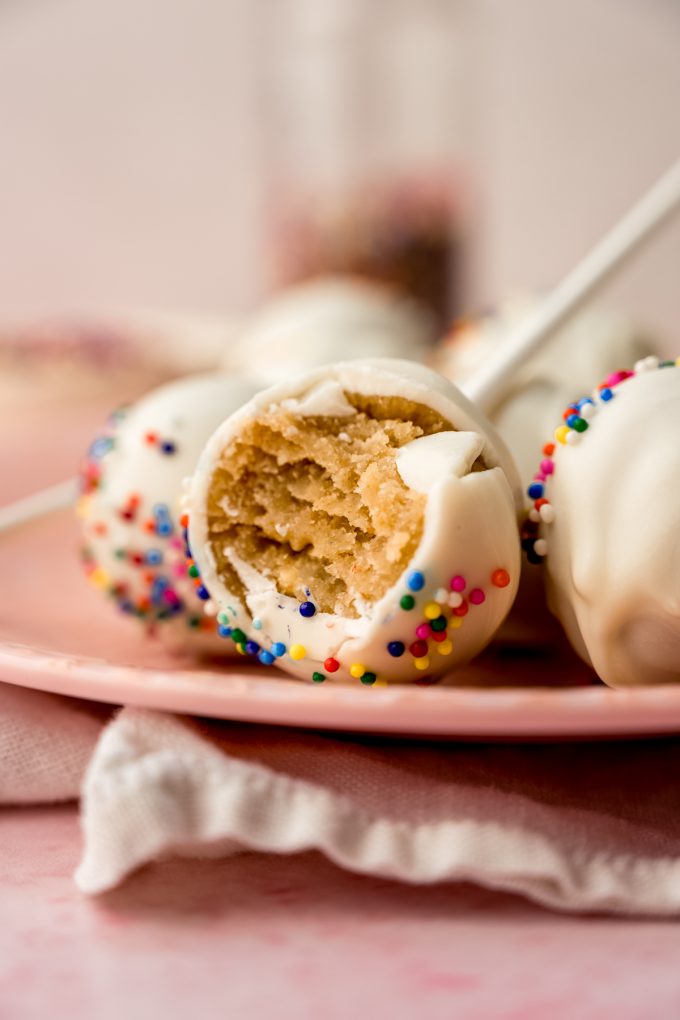 A cake pop with a bite taken out of it on a plate.