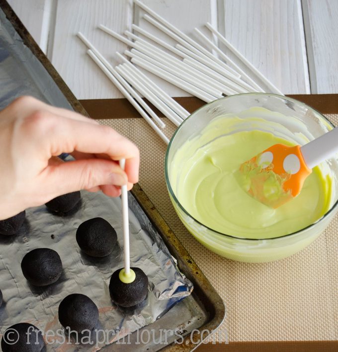 putting a lollipop stick into a cake ball to make cake pops