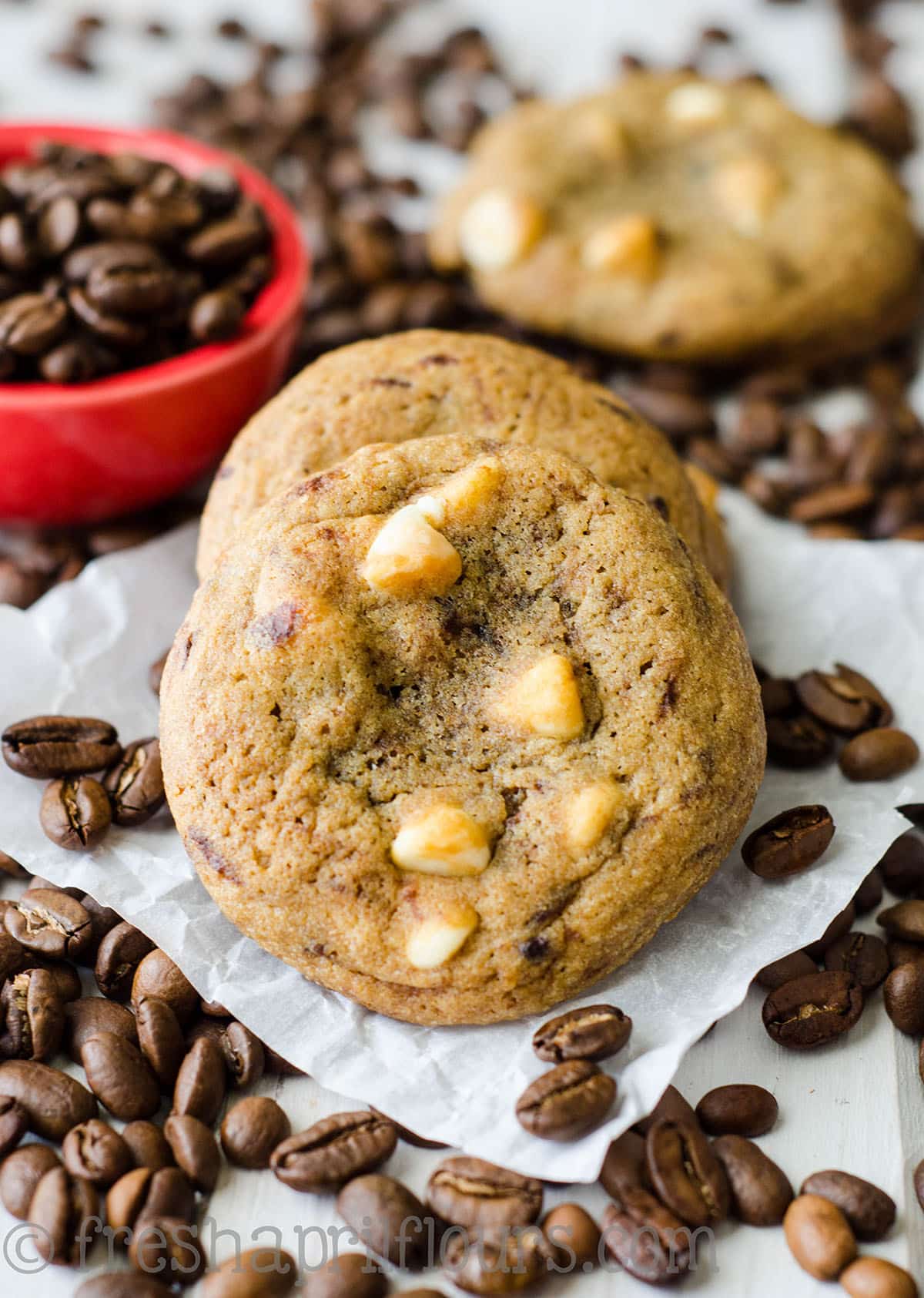 cappuccino cookies on a piece of parchment paper with coffee beans scattered around 
