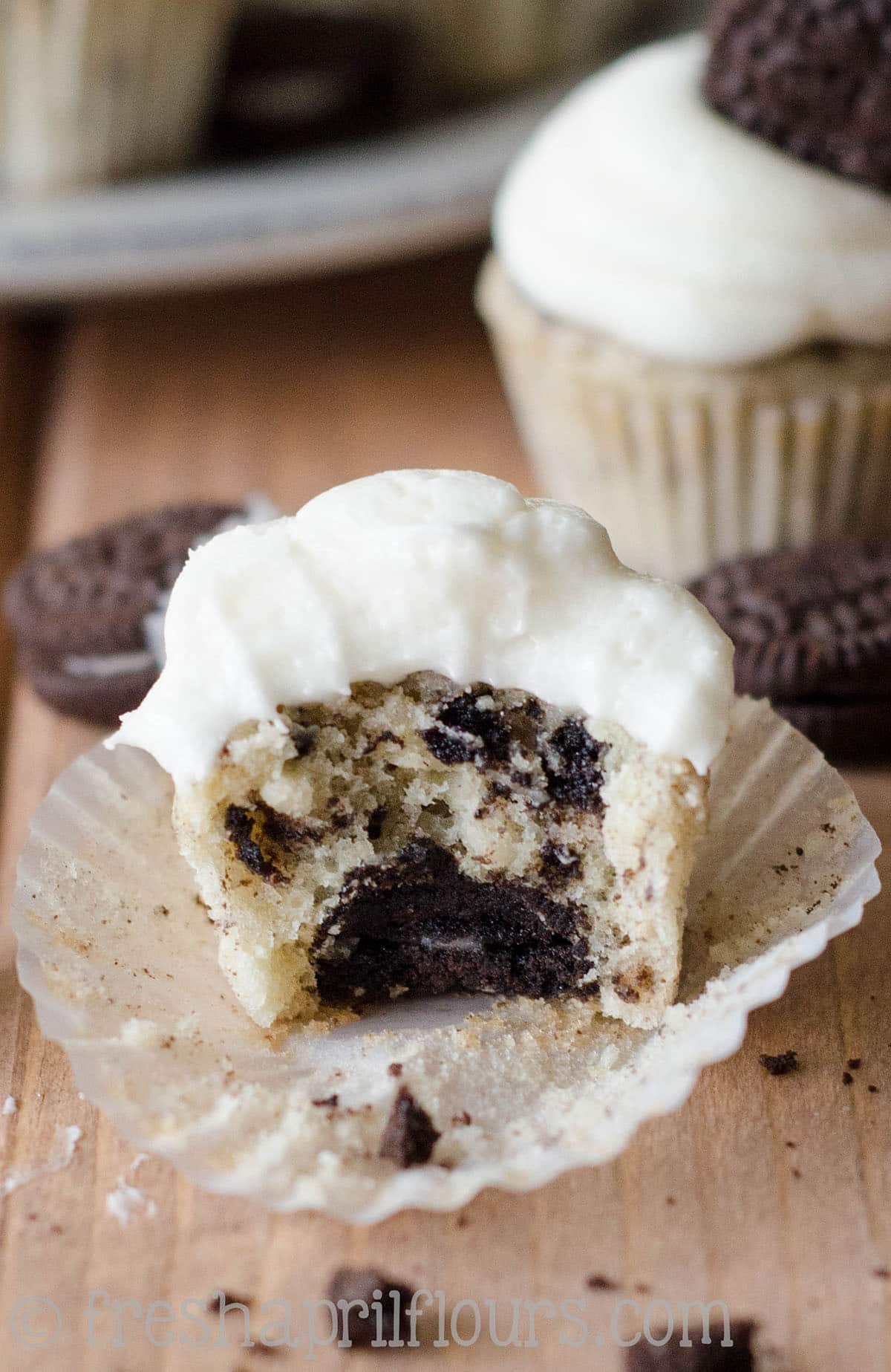 A mini cookies and cream cupcake with a bite taken out of it.