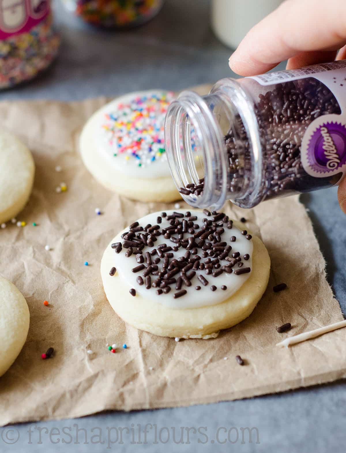 pouring sprinkles onto cut-out sugar cookies