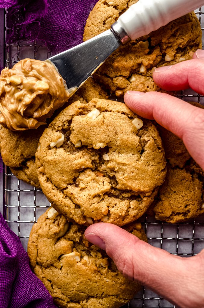 Aerial photo of someone holding a flourless peanut butter cookie over a cooling rack.