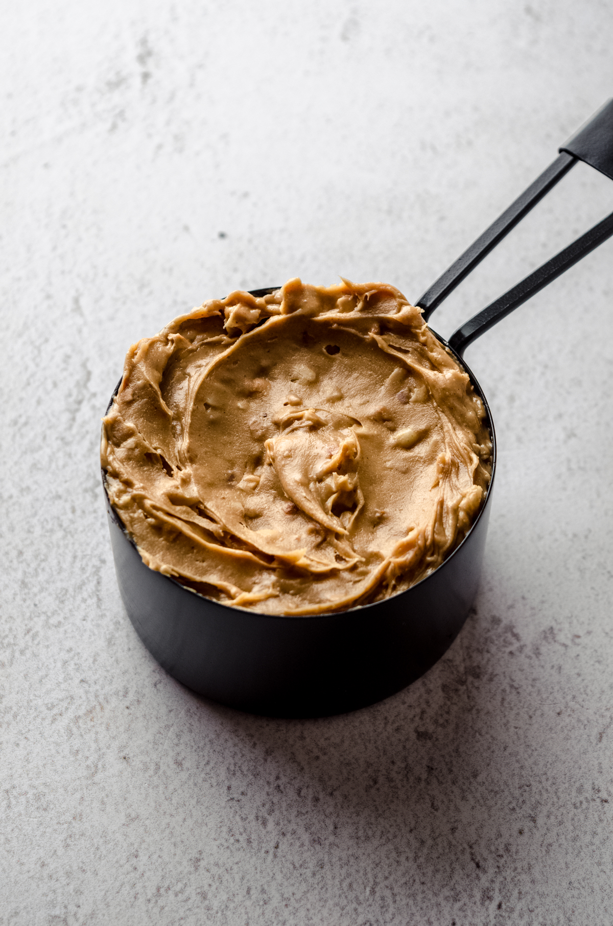 Crunchy peanut butter in a black measuring cup.