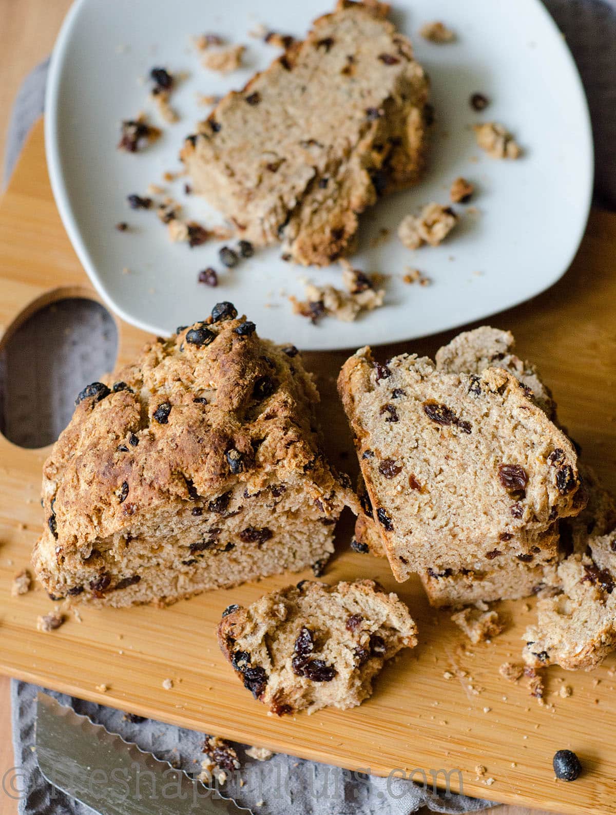 Irish soda bread sliced into pieces and sitting on a cutting board.