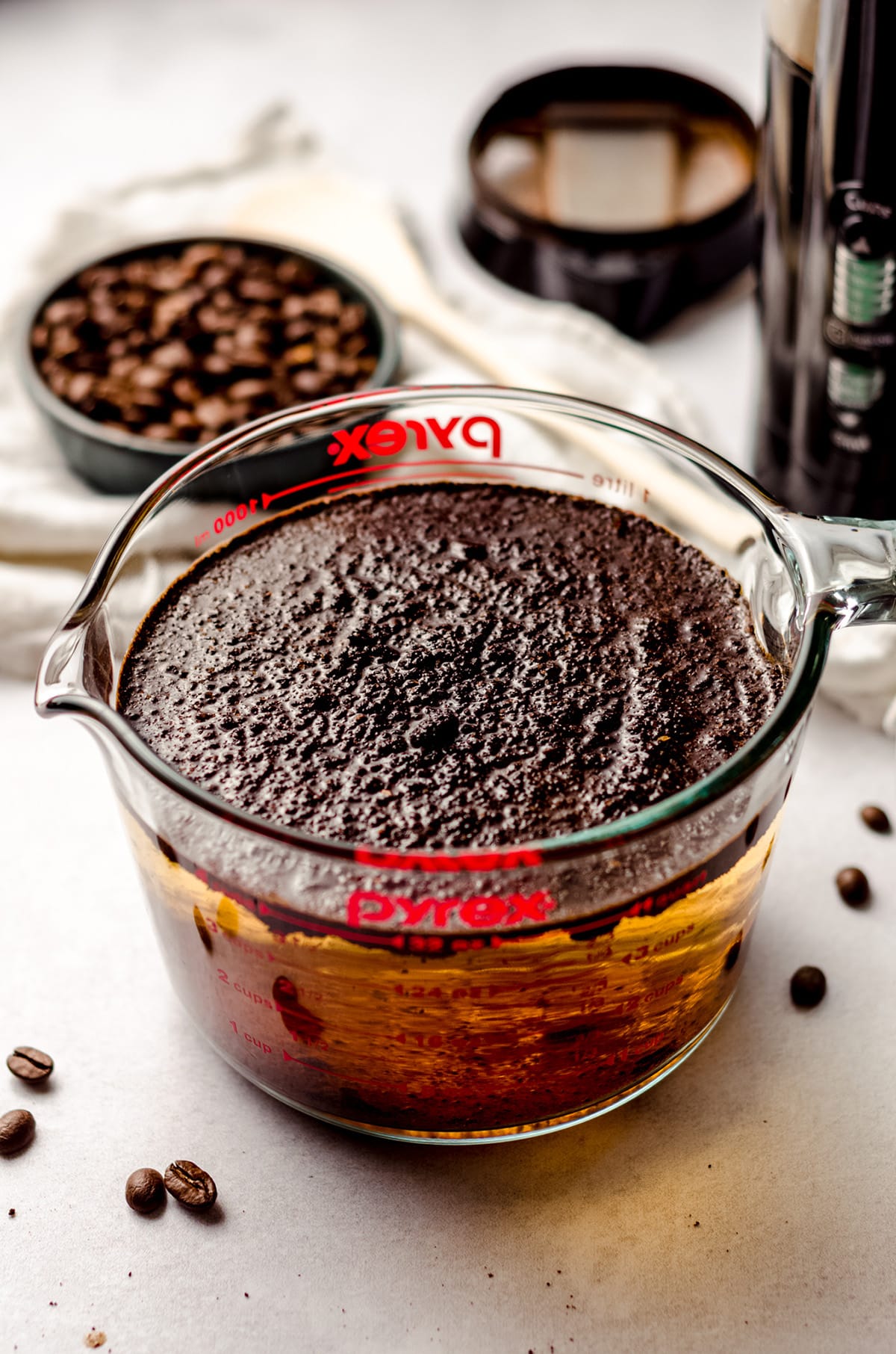 coffee grounds soaking in water in a glass measuring cup