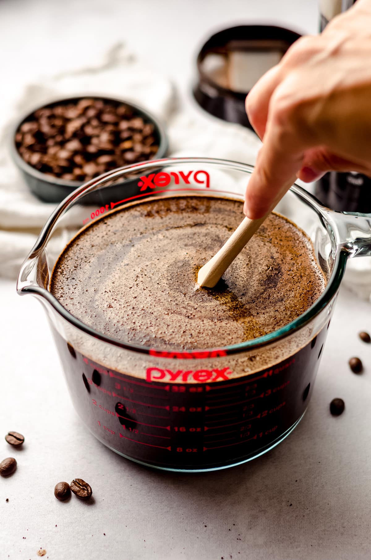 stirring soaked coffee grounds in a glass measuring cup