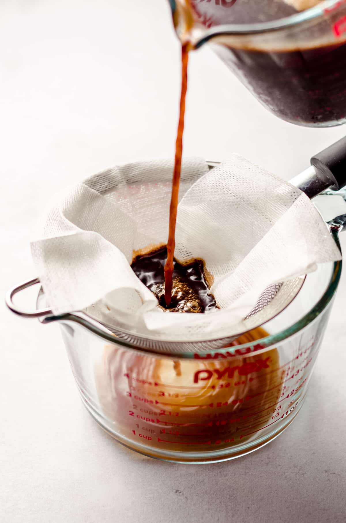 straining soaked coffee grounds through a mesh cloth