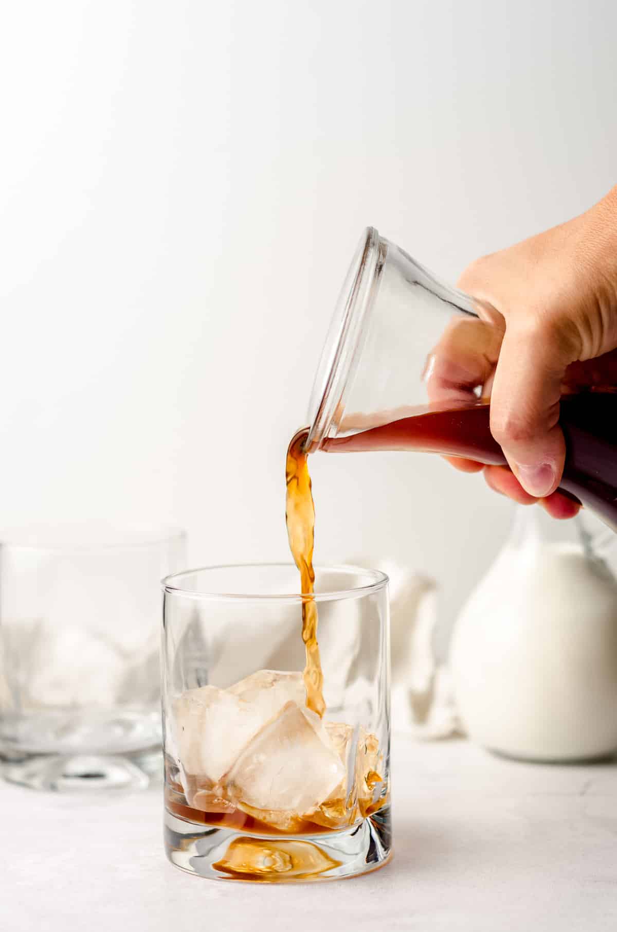 pouring cold brew coffee into a glass with ice