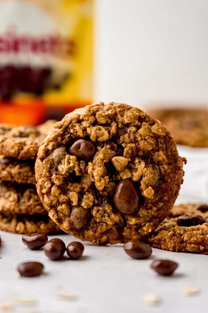 Oatmeal Raisinet cookies on a surface with a bag of Raisinets in the background.