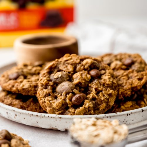 Oatmeal Raisinet cookies on a plate with a bag of Raisinets in the background.