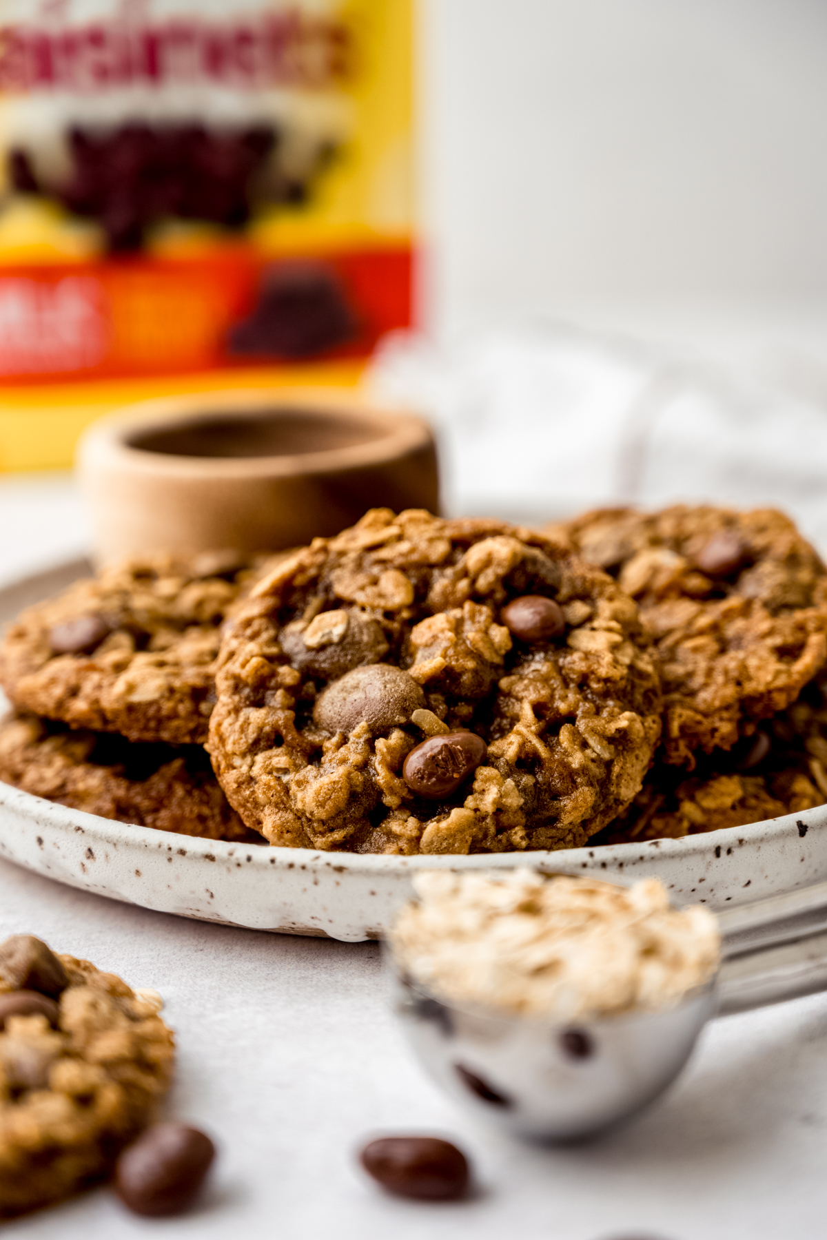 Oatmeal Raisinet cookies on a plate with a bag of Raisinets in the background.