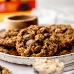 Oatmeal Raisinet cookies on a plate with a bag of Raisinets in the background.
