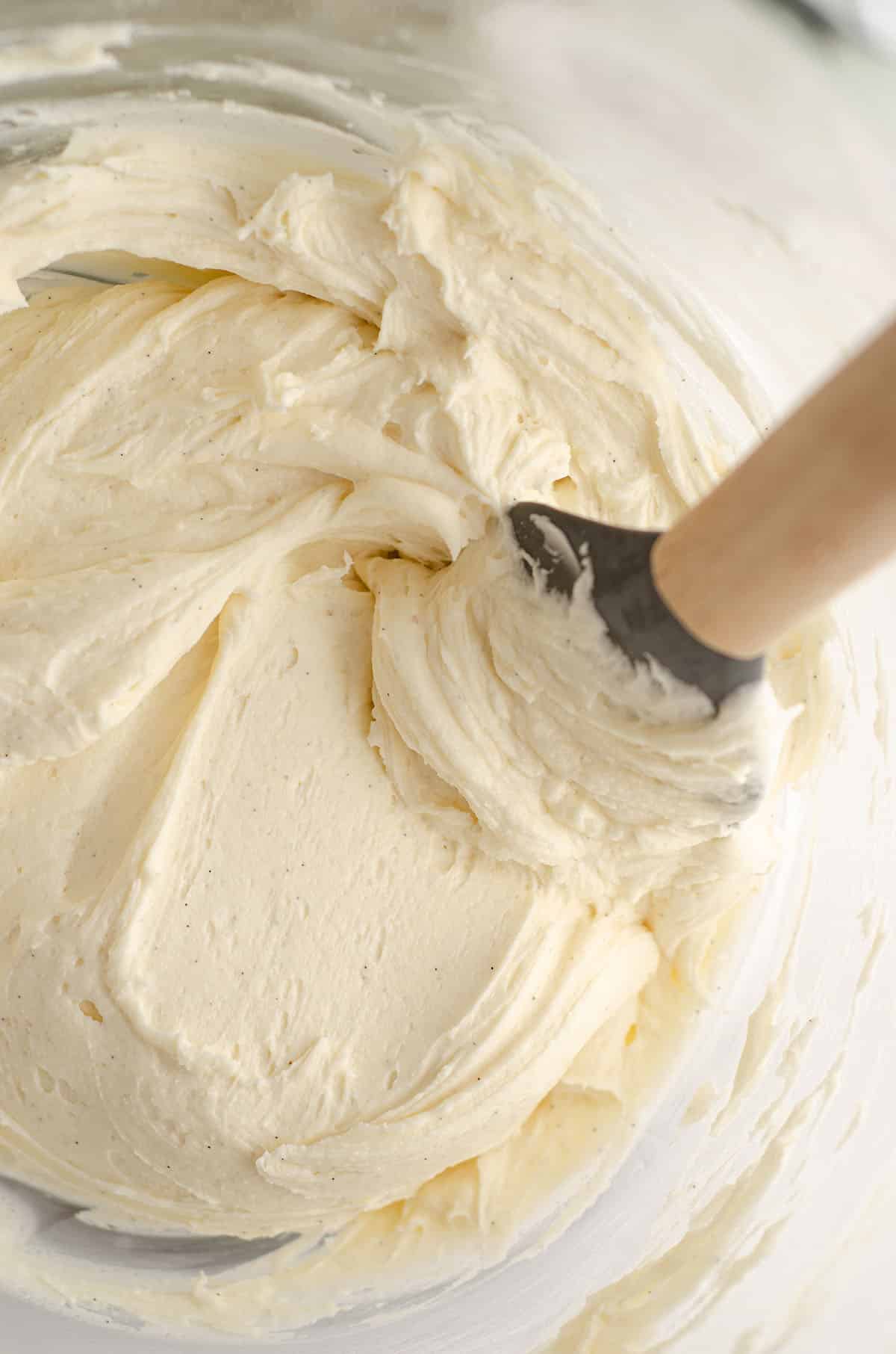 vanilla bean buttercream in a glass bowl with a spatula