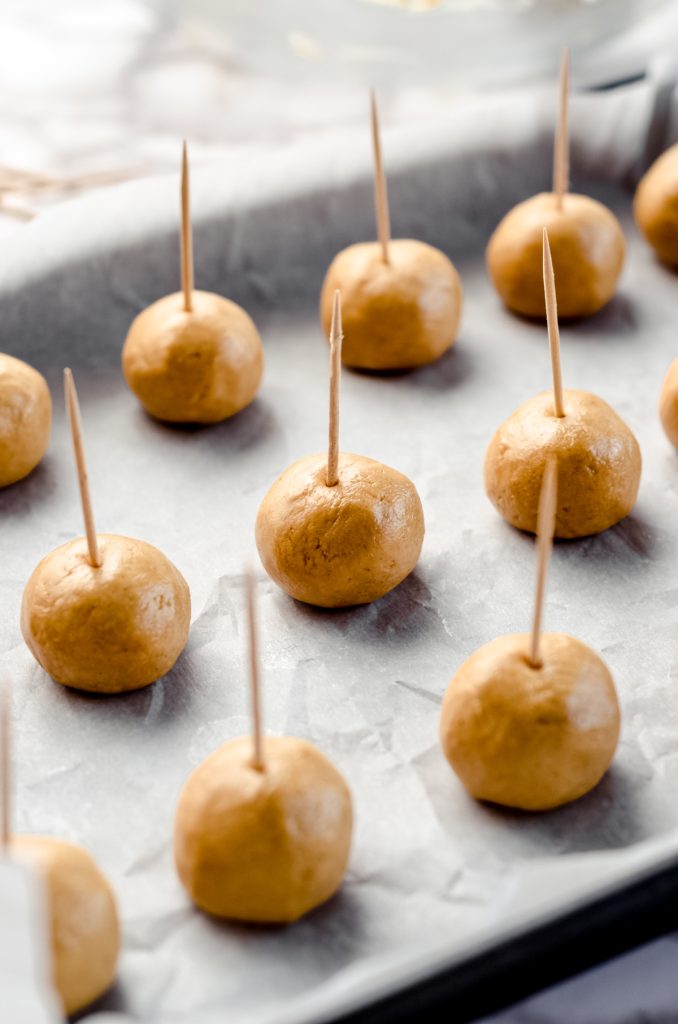 Peanut butter balls with toothpicks in the top ready to make buckeye balls.