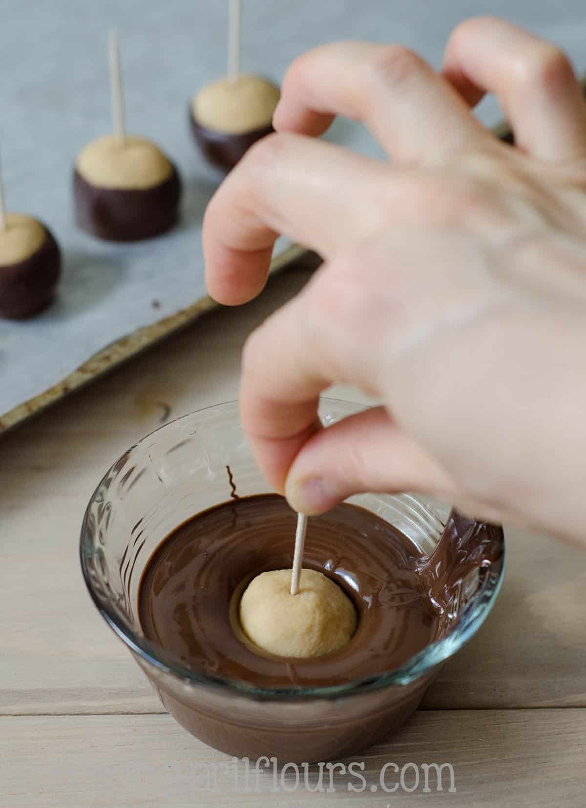 dunking peanut butter buckeye balls into chocolate