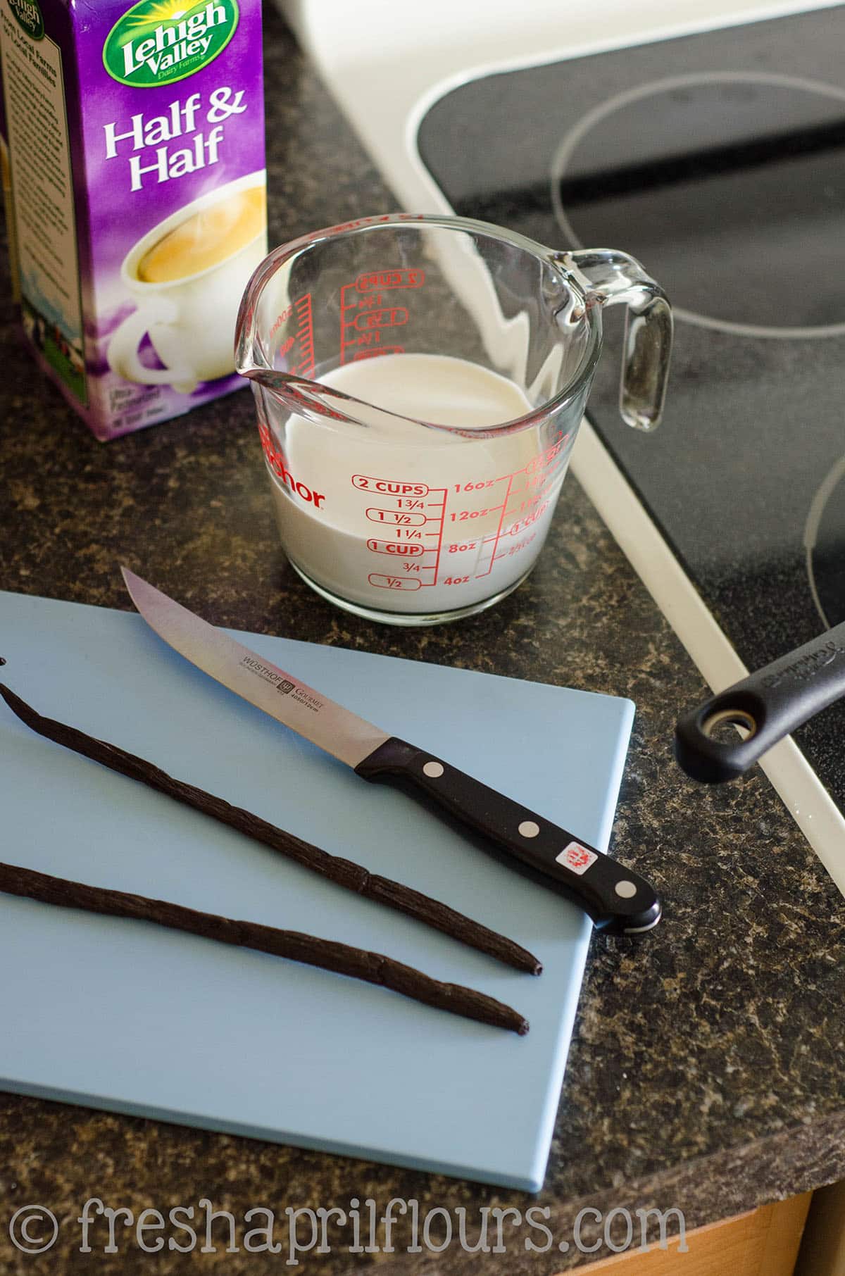 Slicing vanilla beans on a blue cutting board.
