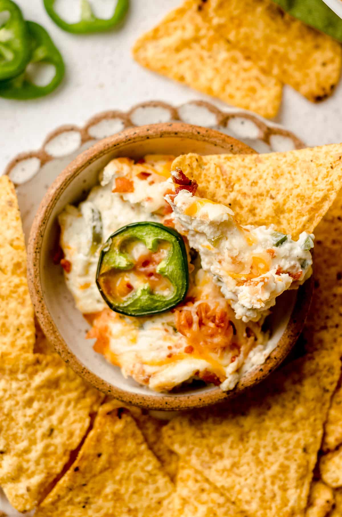 aerial photo of jalapeno cream cheese dip in a bowl on a plate with chips