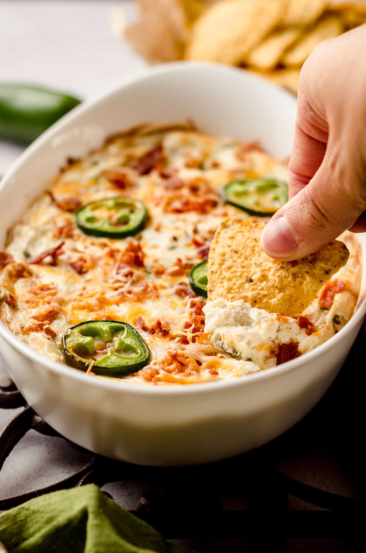 hand dipping a chip in to jalapeno cream cheese dip