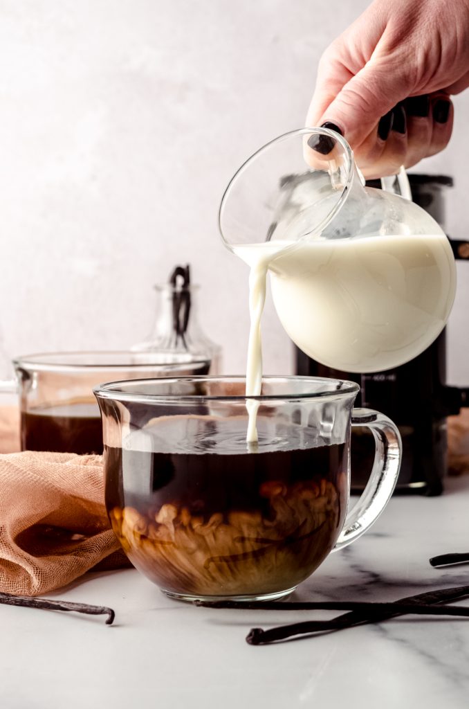 Someone is pouring homemade French vanilla creamer into a mug of coffee.