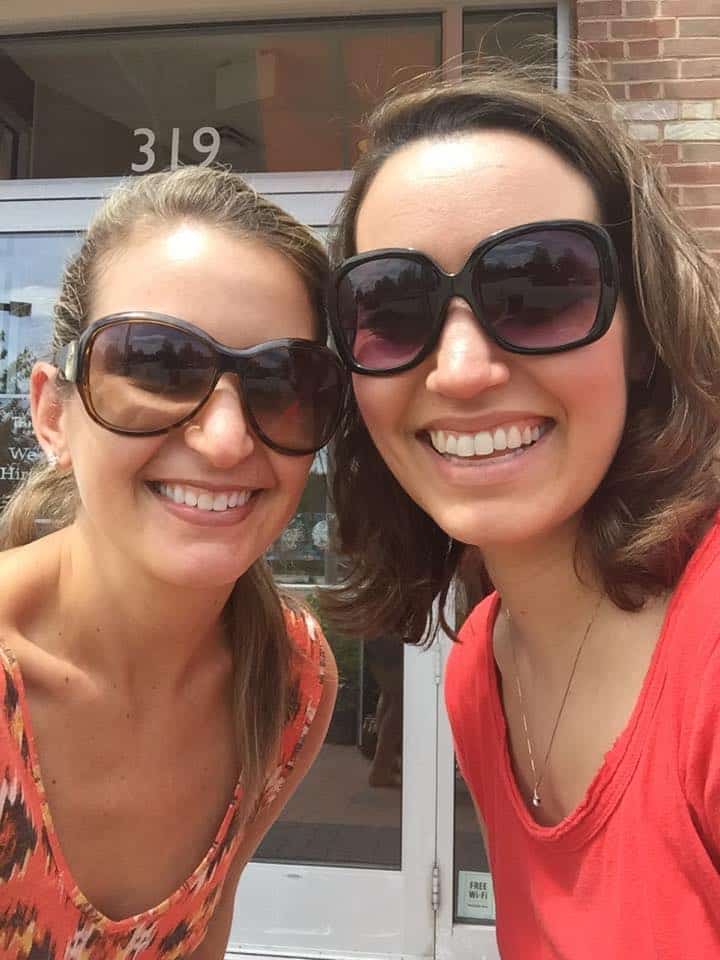 Two women wearing sunglasses and smiling.