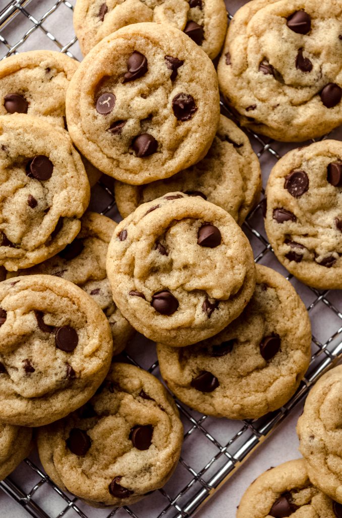 Aerial photo of a bunch of mini chocolate chip cookies on a wire rack.