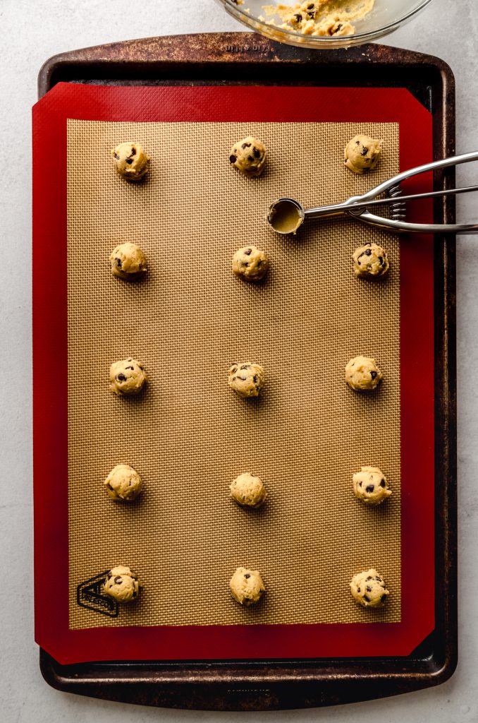 Aerial photo of mini chocolate chip cookies on a baking sheet.