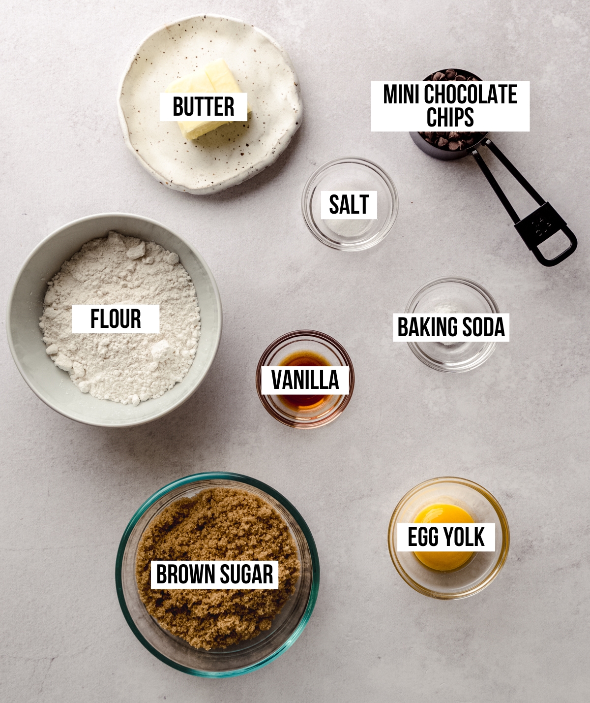 Aerial photo of ingredients to make mini chocolate chip cookies with text overlay labeling each ingredient.