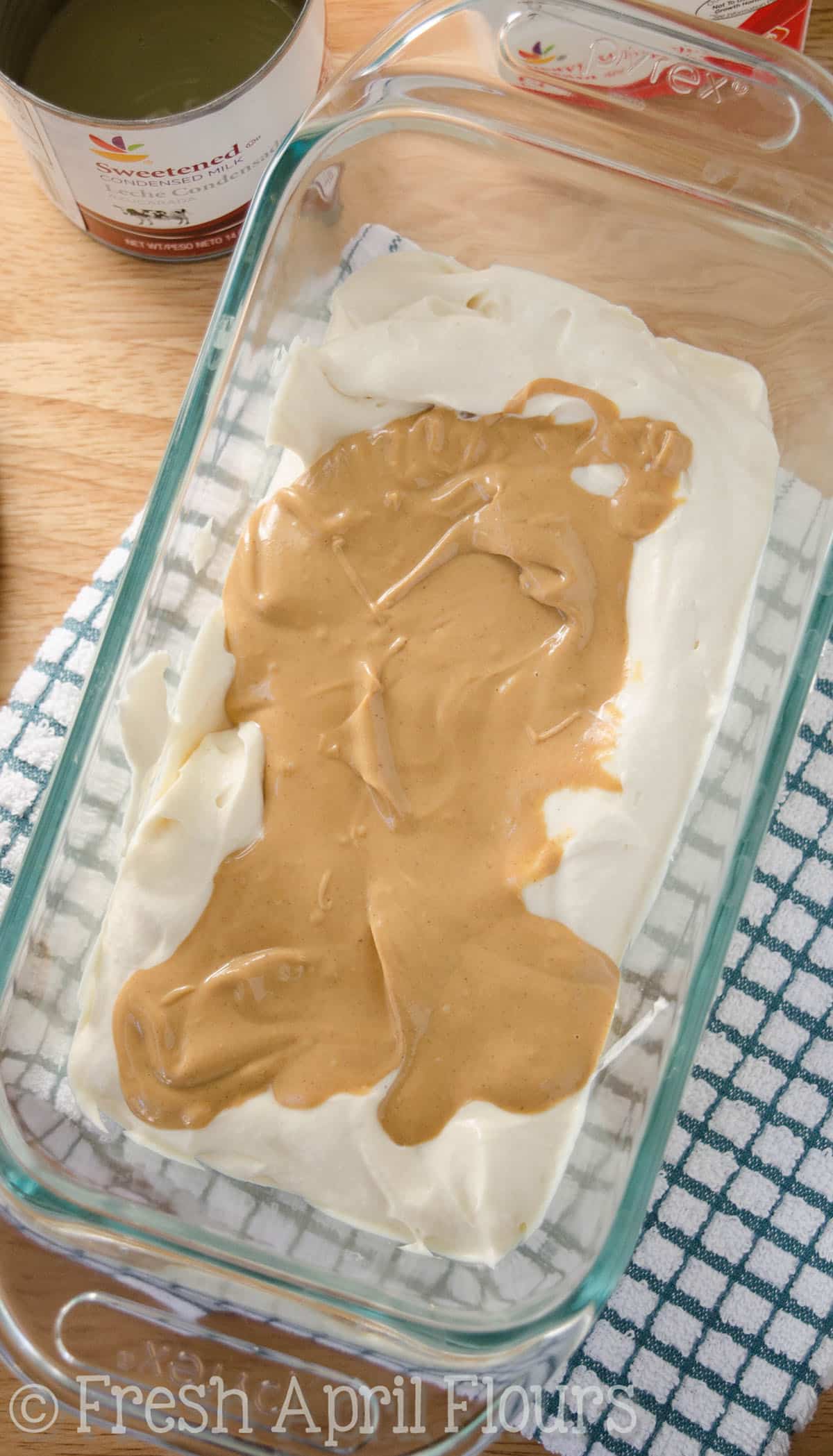 A layer of peanut butter ripple on top of no churn ice cream in a glass dish.