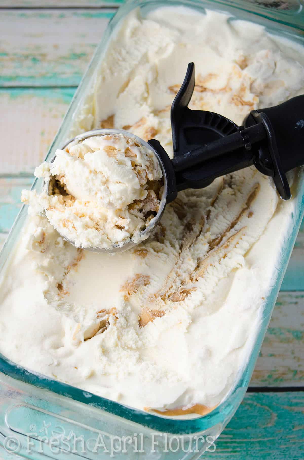 No churn peanut butter ripple ice cream in a glass container with an ice cream scoop.