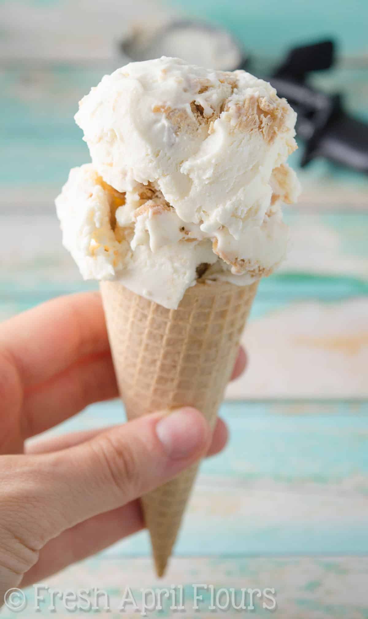 A hand holding an ice cream cone full of no churn peanut butter ripple ice cream.